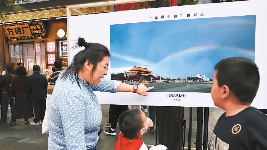 前门大街的游客通过展览上的摄影作品领略中轴线风光。东城区文联供图
